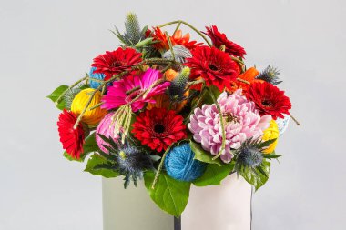 Parlak bir çiçek buketi beyaz arka planda bir hediye kutusunda, en üstte.,