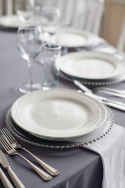 Masa örtüsü olan bir masa, güzel bir porsiyon beyaz tabak, güzel bir tabak, restoranda akşam yemeği.