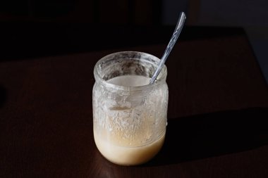 Kirli kavanoz masada duruyor, içinde kaşık olan bulaşıkları yıkamıyor.