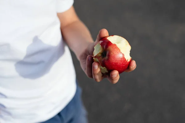 bitten off red apple in children's hands, healthy nutrition concept