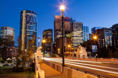 Calgary şehir merkezindeki iş bölgesinin merkezi Cadde Köprüsü'Bow Nehri gece zaman arka planda ikonik Calgary Kulesi ile giren otomobil hareket eden ışık yollar.