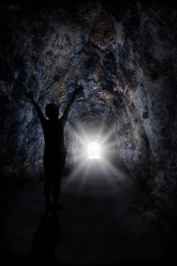 Silhouette of woman raising hands with blinding light at the end of the tunnel. Concept of conquering adversity or success through obstacles. clipart