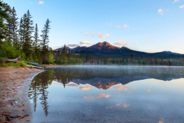 Piramit dağın üzerinden altın gündoğumu patlak ve Edith Gölü Jasper Milli Parkı'nda yüzeyi yansımaları kapalı sakin suları ile düşük sis yerleşir.