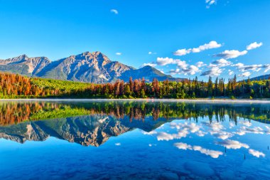 Patricia Gölü Jasper Milli Parkı'nda piramit Dağı arka plan ve sisli sis su yüzeyi üzerinde gündoğumu. Sakin suları sakin yansımaları oluşturma.