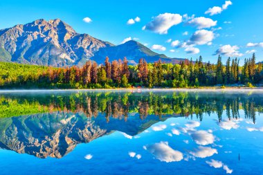 Patricia Gölü Jasper Milli Parkı'nda piramit Dağı arka plan ve sisli sis su yüzeyi üzerinde gündoğumu. Sakin suları sakin yansımaları oluşturma.