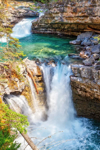 Rushing waterfall flows into the turquoise colored Johnston Canyon creek at Banff National Park in Alberta, Canada. The waters empty into the Bow River.