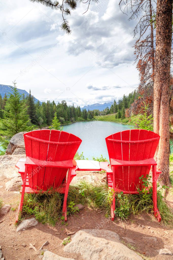 Two red adirondack chairs overlooking the Valley of the Five Lakes on the Icefields Parkway in the Canadian Rockies. They were placed by Parks Canada in select scenic locations throughout Jasper National Park for visitors to enjoy the exquisite view