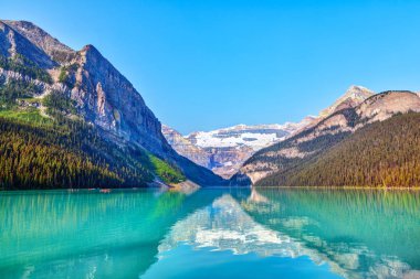 Lake Louise Banff National Park turkuaz göller buzul beslemeli ve Victoria buzul dağ içinde belgili tanımlık geçmiş. Uzaktan kırmızı Kano kürek çekmeye ziyaretçi.