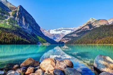 Lake Louise Banff National Park turkuaz göller buzul beslemeli ve Victoria buzul dağ içinde belgili tanımlık geçmiş. Uzaktan kırmızı Kano kürek çekmeye ziyaretçi.