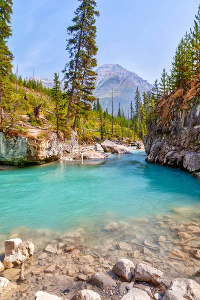 Turquoise colored waters from Tokumm Creek flows through Marble Canyon in Kootenay National Park, British Columbia, Canada, near Banff. Mount Whymper in the background.