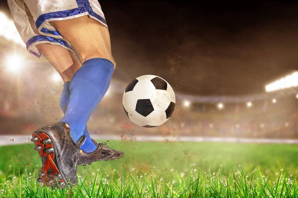 Soccer player in action with football in brightly lit outdoor stadium. Focus on foreground and soccer ball with shallow depth of field on background and copy space.