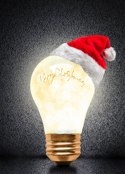 发光的灯泡戴着圣诞老人的帽子与圣诞快乐的消息和复制空间 发光的圣诞节和一个明亮的新年 — 图库照片
