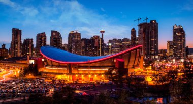 Calgary şehir manzarası ikonik Saddledome arena ve Calgary kule şehir gökdelenler çevreleyen ile arka planda gösterilen günbatımı mavi saatte Panoraması.