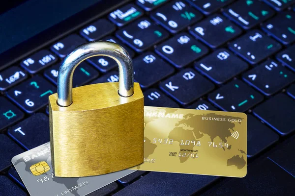 Golden padlock on top of fictitious credit cards on computer keyboard. Concept of Internet security, data privacy, cybercrime prevention for online shopping transaction payments.