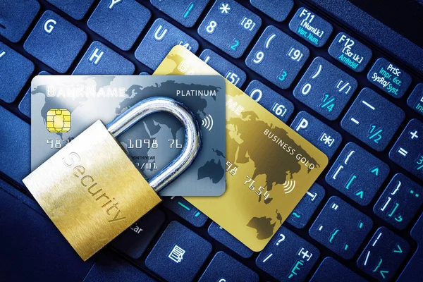 Golden padlock on top of fictitious credit cards on computer keyboard. Concept of Internet security, data privacy, cybercrime prevention for online shopping transaction payments.