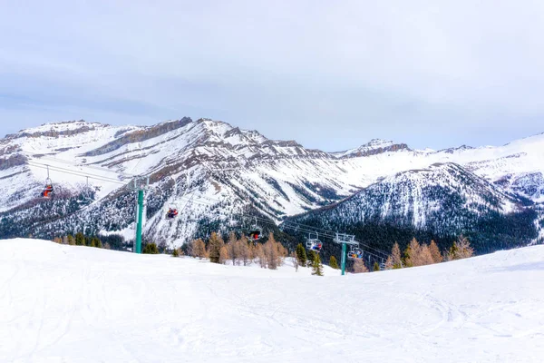 Esquiadores en telesilla suben una pista de esquí en las Montañas Rocosas canadienses — Foto de Stock