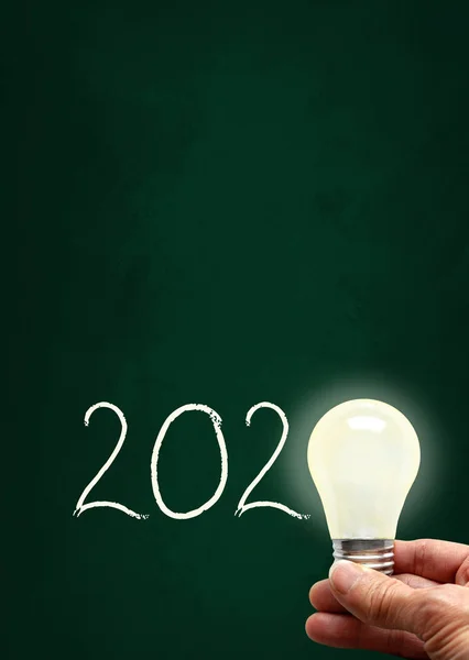 New Year 2020 Lighted Bulb on Chalkboard and Copy Space