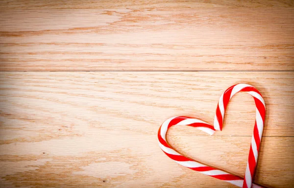 Canne da zucchero natalizie a forma di cuore sulla tavola di legno — Foto Stock