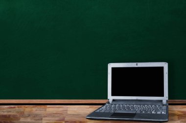 Sınıfta okula dönüş konsepti, masadaki dizüstü bilgisayarın karatahtadaki kopya alanı göstermesini gösteriyor.