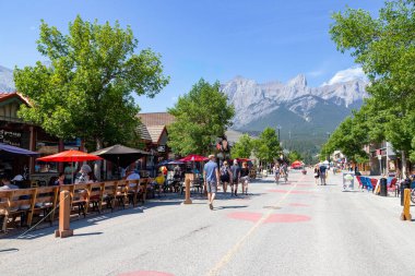 Canmore, Kanada - 30 Temmuz 2020: Kanada Kayalıkları 'nda Canmore şehir merkezinde gezen ve yemek yiyen turistler. Yol, ziyaretçiler arasında daha fazla sosyal mesafeye olanak sağlamak amacıyla COVID-19 nedeniyle trafiğe kapatıldı.