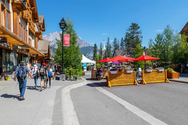 BANFF, CANADA - 29 Temmuz 2020: Turistler Banff Ulusal Parkı 'nda Banff Bulvarı boyunca yürüyüp yemek yiyorlar. Sokak, ziyaretçiler arasında daha fazla sosyal mesafeye izin verilmesi için COVID-19 nedeniyle kapatıldı.