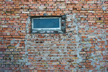 Duvardaki eğri büğrü bir pencere, sert tuğla ve çimento parçaları.