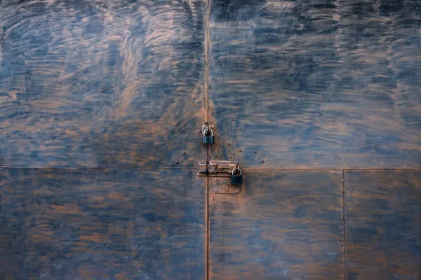 Kabaca boyanmış iki asma kilitli bir kapının tam ekran dokusu