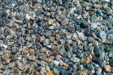 Açık ve sığ bir deniz suyunda çok renkli çakıl taşlarının dokusu