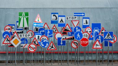 Gri kıvrımlı metal arka plan, yatay ve panoramik üzerinde birçok yol işareti var.