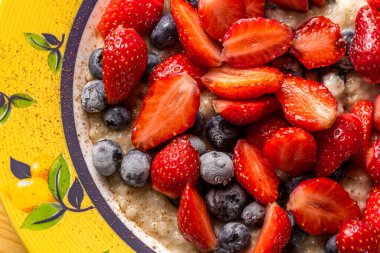 Sağlıklı kahvaltı - Taze çilekli yulaf ezmesi ve masadaki tarçınlı donmuş yaban mersini