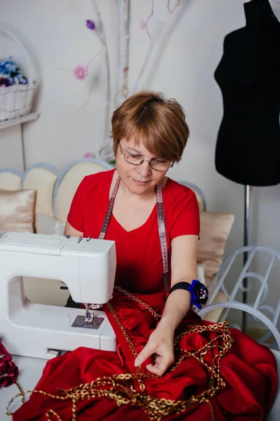 赤い服を着た女性の裁縫師の女性は ミシンで縫います アトリエ 仕立てのプロセス — ストック写真
