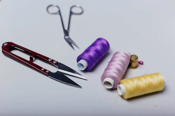 Threads for sewing, Scissors on the table. Tools in the sewing studio