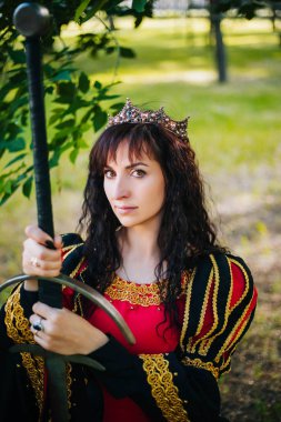Kraliçe onu elinde bir kılıç ile. Taç güzel kız. Fantezi. Altın nakış ile Ortaçağ siyah ve kırmızı elbise.