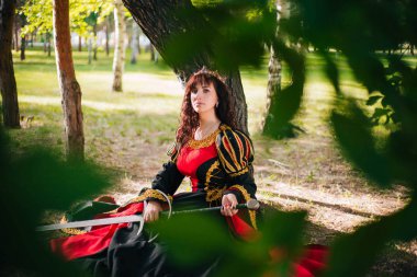 Kraliçe onu elinde bir kılıç ile. Taç güzel kız. Fantezi. Altın nakış ile Ortaçağ siyah ve kırmızı elbise.