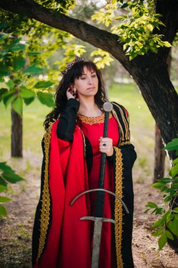 Kraliçe onu elinde bir kılıç ile. Taç güzel kız. Fantezi. Altın nakış ile Ortaçağ siyah ve kırmızı elbise.