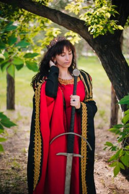 Kraliçe onu elinde bir kılıç ile. Taç güzel kız. Fantezi. Altın nakış ile Ortaçağ siyah ve kırmızı elbise.