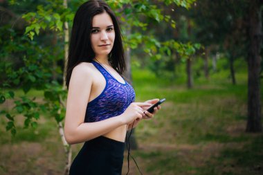 Genç güzel kız ile hareket eden telefon. Spor giyim onun elinde bir akıllı telefon ile kulaklıklar giyen bir kadın. Sağlıklı bir yaşam tarzı. Müzik.
