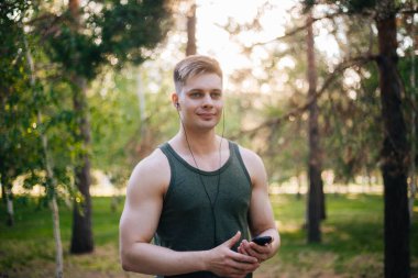 Yakışıklı genç bir adam. Müzik üstünde senin smartphone seçer. Kulaklıklar ve bir cep telefonu ile bir adam.