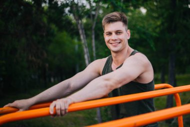 Genç yakışıklı olan bir spor yatay çubuklar üzerinde çalışmaktadır. Sağlıklı yaşam tarzı