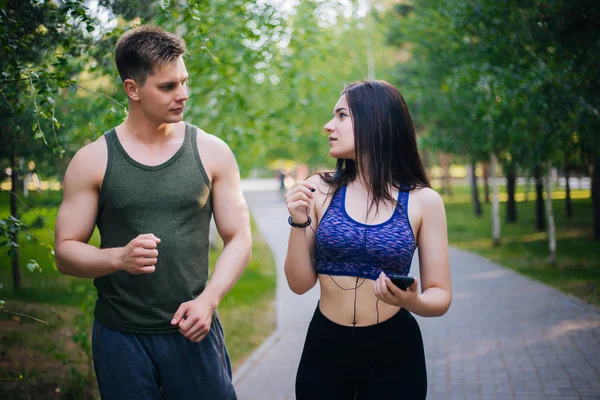 A young girl and a guy are running around the park. Doing sports outdoors. People in sportswear make a run. Leisure
