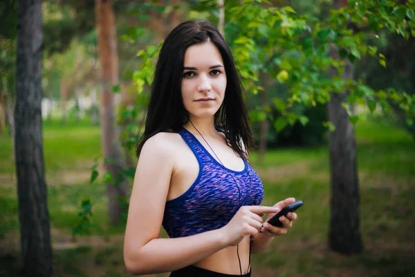 Genç güzel kız ile hareket eden telefon. Spor giyim onun elinde bir akıllı telefon ile kulaklıklar giyen bir kadın. Sağlıklı bir yaşam tarzı. Müzik.