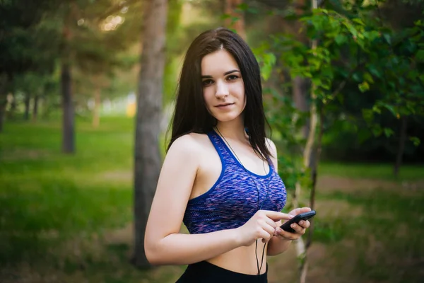Genç güzel kız ile hareket eden telefon. Spor giyim onun elinde bir akıllı telefon ile kulaklıklar giyen bir kadın. Sağlıklı bir yaşam tarzı. Müzik.