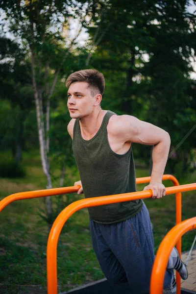 Genç yakışıklı olan bir spor yatay çubuklar üzerinde çalışmaktadır. Sağlıklı yaşam tarzı