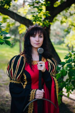 Kraliçe onu elinde bir kılıç ile. Taç güzel kız. Fantezi. Altın nakış ile Ortaçağ siyah ve kırmızı elbise.