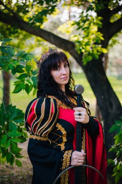 Kraliçe onu elinde bir kılıç ile. Taç güzel kız. Fantezi. Altın nakış ile Ortaçağ siyah ve kırmızı elbise.