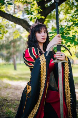 Kraliçe onu elinde bir kılıç ile. Taç güzel kız. Fantezi. Altın nakış ile Ortaçağ siyah ve kırmızı elbise.