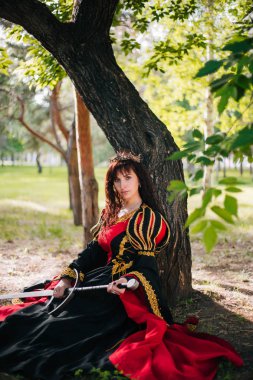 Kraliçe onu elinde bir kılıç ile. Taç güzel kız. Fantezi. Altın nakış ile Ortaçağ siyah ve kırmızı elbise.