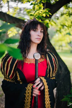 Kraliçe onu elinde bir kılıç ile. Taç güzel kız. Fantezi. Altın nakış ile Ortaçağ siyah ve kırmızı elbise.