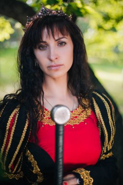 Kraliçe onu elinde bir kılıç ile. Taç güzel kız. Fantezi. Altın nakış ile Ortaçağ siyah ve kırmızı elbise.