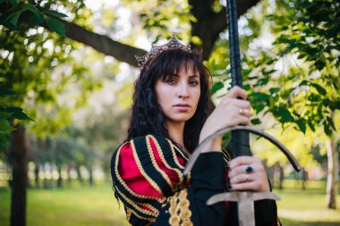 Kraliçe onu elinde bir kılıç ile. Taç güzel kız. Fantezi. Altın nakış ile Ortaçağ siyah ve kırmızı elbise.